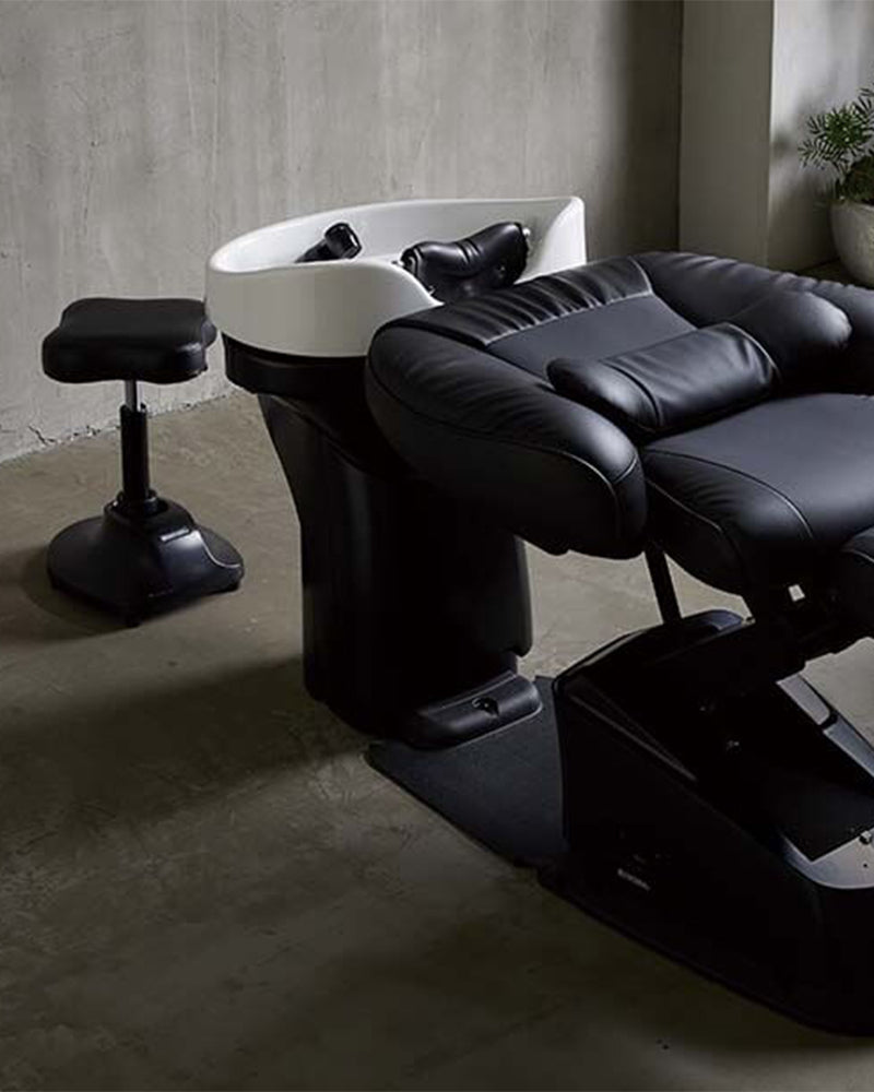 Miljøbillede fra eksklusiv frisørsalon med beton vægge og gulv. Vaks og behandler stol i midten